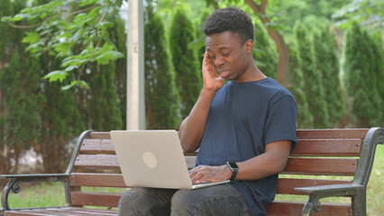 Stressed Casual African Man with Laptop on Park Bench