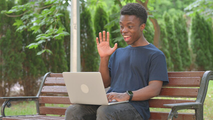 Casual African Man Doing Video Call on Laptop in Park