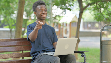 African American Man Pointing Directly at Viewer with Laptop Outdoors