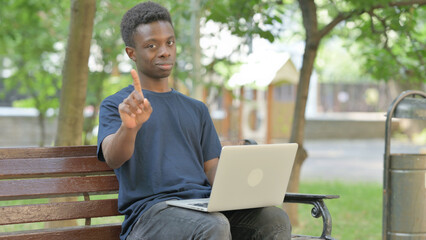 African American Man in Park with Laptop Showing a No Gesture
