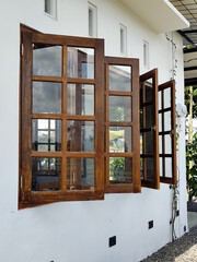 The view of the outer corner of the clean white-walled building shows dark brown wooden windows...