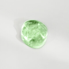 Green cosmetic gel drop on a white background