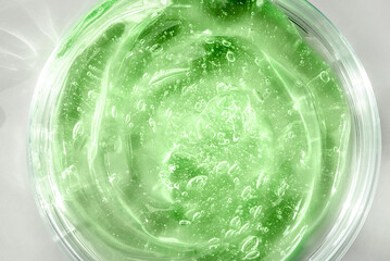 Green cosmetic gel in a round jar on a white background
