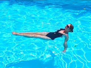 woman in black swimwear is swiming on the back