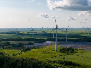 Aerial view of a solar farm and wind turbines in a lush green landscape under a clear sky