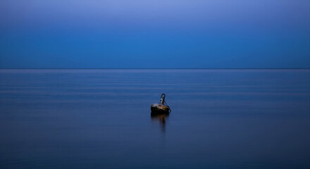 A single buoy floats serenely on a calm, dark blue sea at twilight