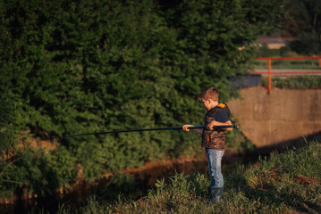 Young fisherman casting line in peaceful river at sunset