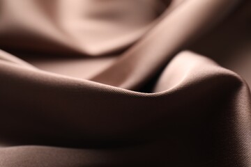 Crumpled light brown silk fabric as background, closeup