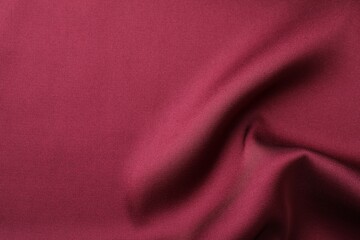 Crumpled burgundy silk fabric as background, top view