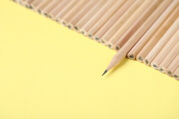 Many graphite pencils on yellow background, closeup. Space for text