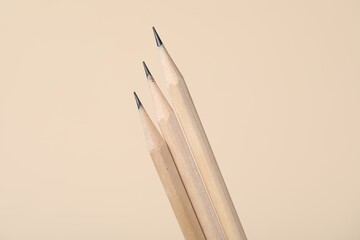 Three graphite pencils on beige background, closeup