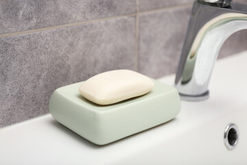 Soap bar near faucet on sink in bathroom, closeup