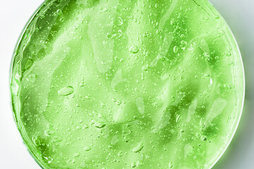 Green cosmetic gel in a round jar on a white background