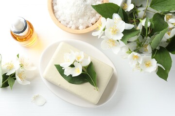 Soap bar, sea salt, essential oil and jasmine flowers on white wooden table, flat lay