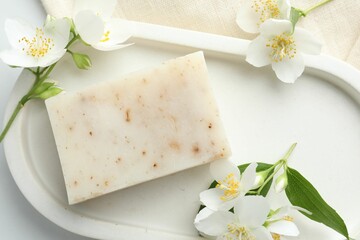 Soap bar and jasmine flowers on white table, flat lay
