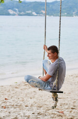 Young Man Relaxing on a Swing at a Beachside Retreat