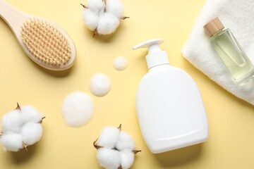 Flat lay composition with bottle of liquid soap and cotton flowers on yellow background