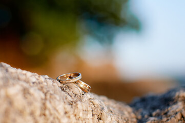 Beautiful wedding rings resting on a rugged stone surface, surrounded by a soft, nature-focused backdrop, symbolizing love and unity in a serene and rustic setting.