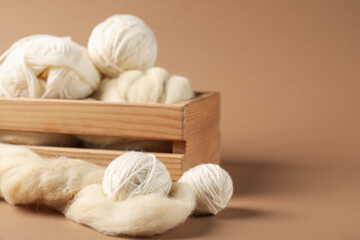 Felting wool and knitting yarn on brown background, closeup. Space for text