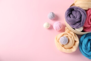 Felting wool and knitting yarn on pink background, flat lay. Space for text