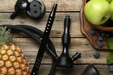 Traditional hookah parts, charcoal rings, fruits, blueberries and mint on wooden table, flat lay