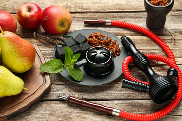 Hookah, coal and fresh fruits on wooden table, closeup