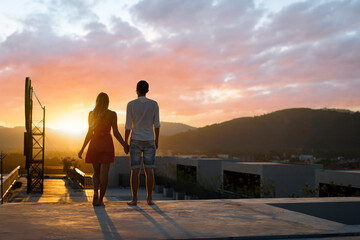 Obraz premium Couple Holding Hands Watching a Scenic Urban Sunset Together