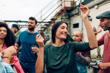 Friends enjoying rooftop party, dancing and drinking beer