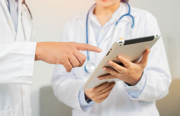 Two doctors working together using a digital tablet discuss patient anamnesis or checkup results together.