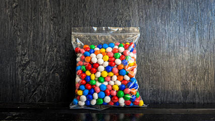 snack in clear plastic packaging on black background - Colorful Ball Biscuits are ball-shaped biscuits coated in colorful chocolate. These biscuits are popular as a favorite snack for children