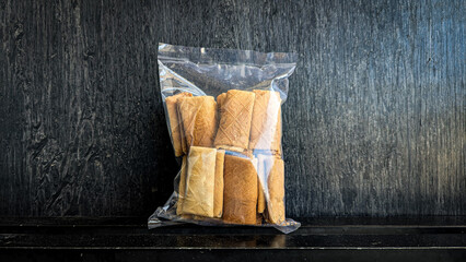 snack in clear plastic packaging on black background - Semprong cake is a traditional Indonesian snack made from rice flour, coconut milk, eggs, and sugar dough that has a crispy texture
