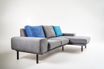 Stylish gray sectional sofa adorned with blue accent cushions, photographed against a clean white...