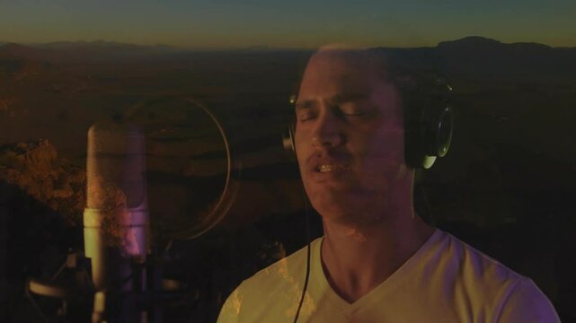 Singer adjusting headphones, tapping mic, singing and recording verse under animated canyon sky