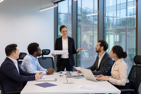 A diverse group of business professionals collaborating in a modern office meeting room, discussing strategy and ideas.