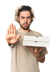 Young man holds pizza boxes for delivery standing with outstretched hand showing stop sign,...