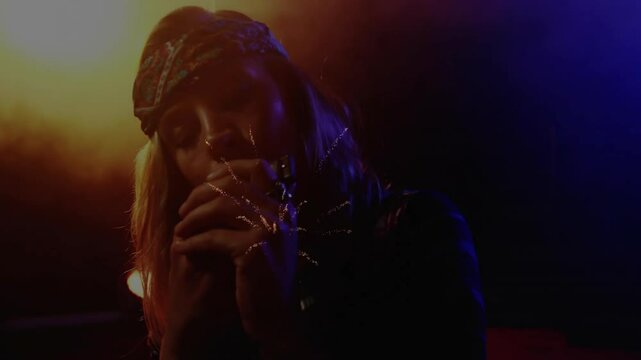 Female singer holding mic closing eyes under music spotlights causing pulsing sparks enriching song