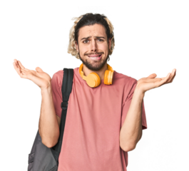 Young student with backpack and headphones confused and doubtful shrugging shoulders to hold a copy space.