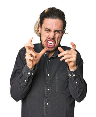 Young Caucasian man in studio setting upset screaming with tense hands.