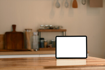 Digital tablet with blank screen on wooden kitchen counter