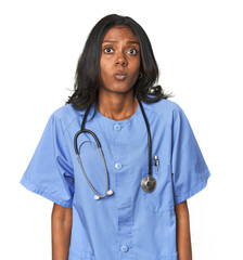 Young Indian nurse with stethoscope shrugs shoulders and open eyes confused.