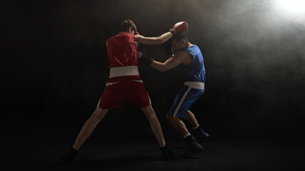 Two boxers exchange punches under a dramatic spotlight in smoky arena. Concept of intense...