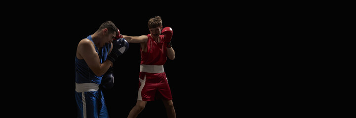 Boxers engaged in an intense sparring match share focused expressions, set against a black...