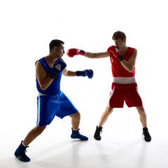 Two boxers are sparring in a brightly lit studio, each wearing red and blue sports gear as they...
