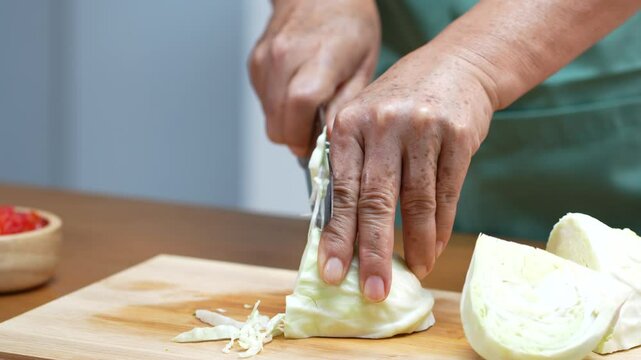 Closeup of male hands slicing Cabbage on a wooden board in the kitchen, preparing to cook.