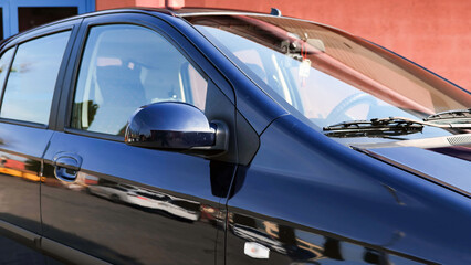 Fototapeta premium Clean and shiny dark blue car parked near building reflecting surrounding in the paint