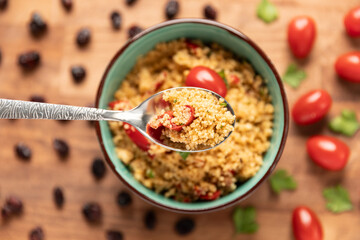 Top view of a scoup of Moroccan couscous salad with fresh cherry tomatoes.