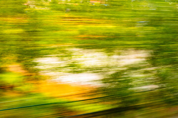 Dynamic motion blur view from high-speed train window: Green landscape, trees & fields rush past at...