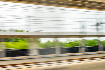 Dynamic motion blur view from high-speed train window: Green landscape, trees & fields rush past at...