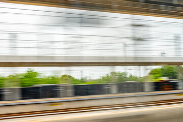 Dynamic motion blur view from high-speed train window: Green landscape, trees & fields rush past at high speed