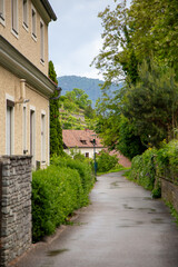 A charming narrow street in the Austrian village of Spitz, captured on a quiet summer day. The cobblestone path winds between traditional houses with rustic facades, bathed in warm natural light.